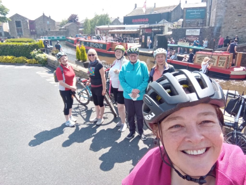 Group selfie of women cyclists by the canal.
