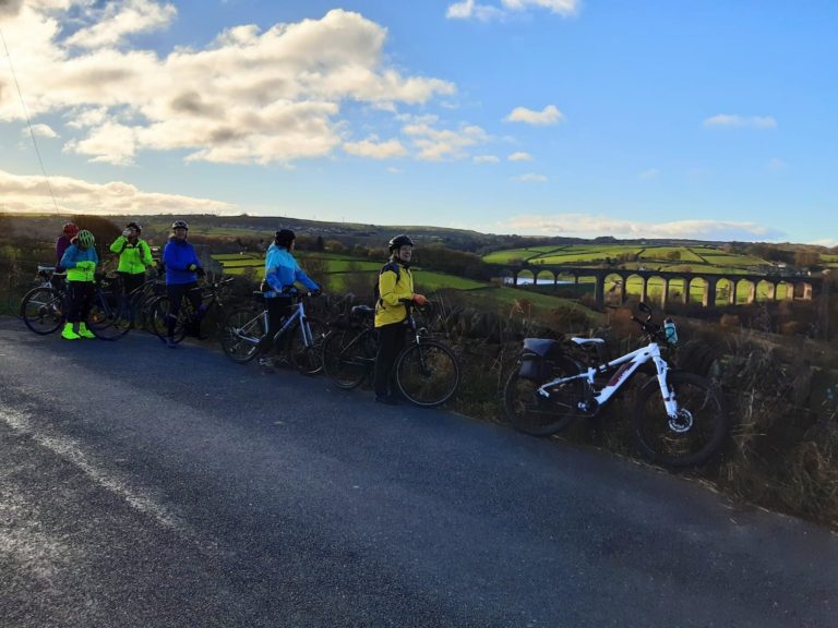 Cyclists with viaduct in distance.