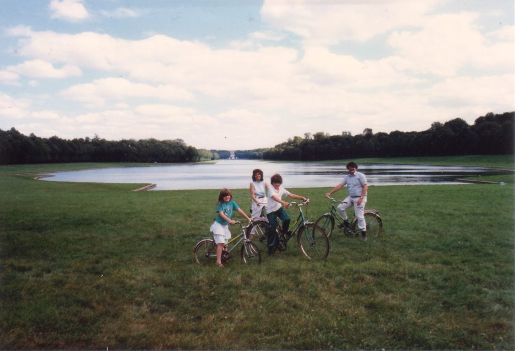 Family on bikes in front of lake.