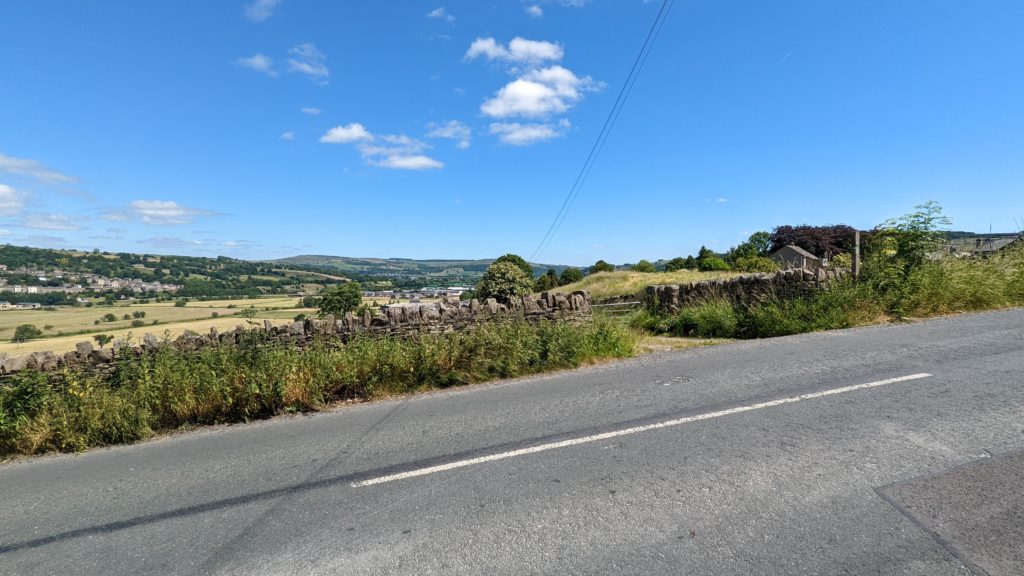 Road with stone wall and hills in background.