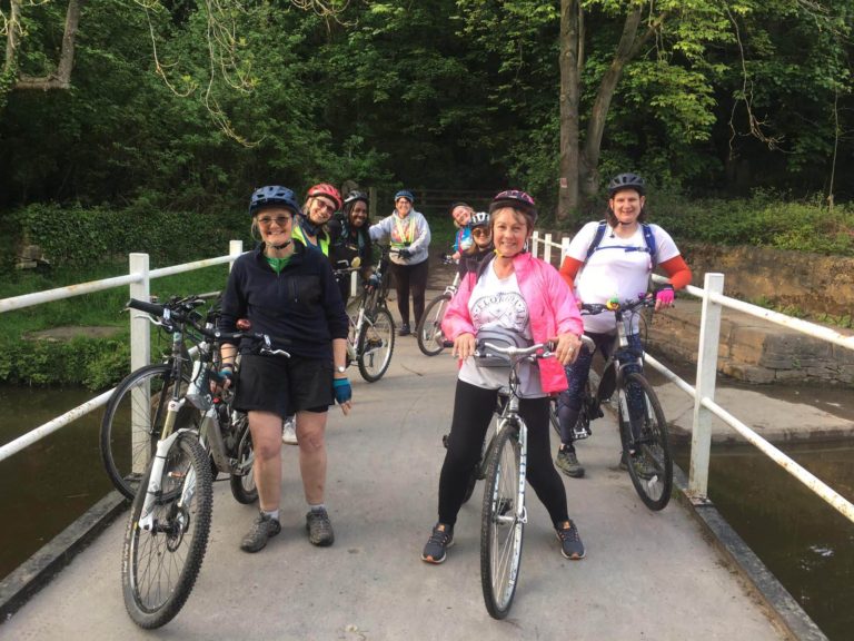 Women on bikes on a bridge.