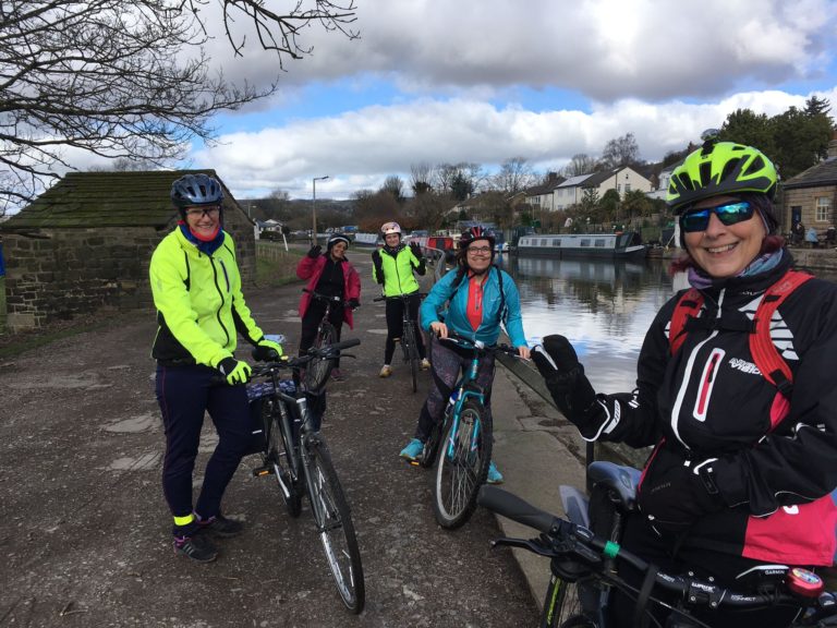 Women on bikes by canal.