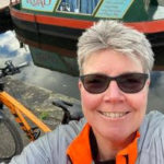 Jayne 5 Smiling woman in sunglasses next to narrowboat.