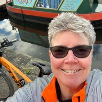 Smiling woman in sunglasses next to narrowboat.