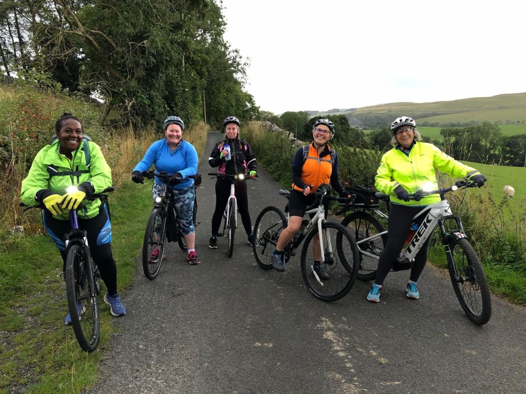 Group of women cyclists halted on a country lane for a photo