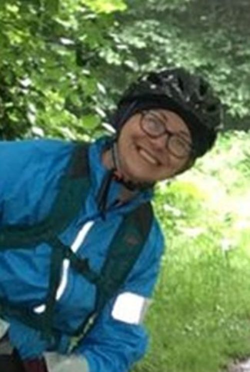 Woman smiling in cycling jacket and helmet.