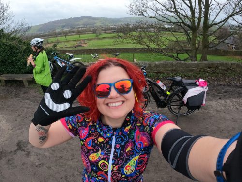 Smiling cyclist with sunglasses on and a smiley face on glove.