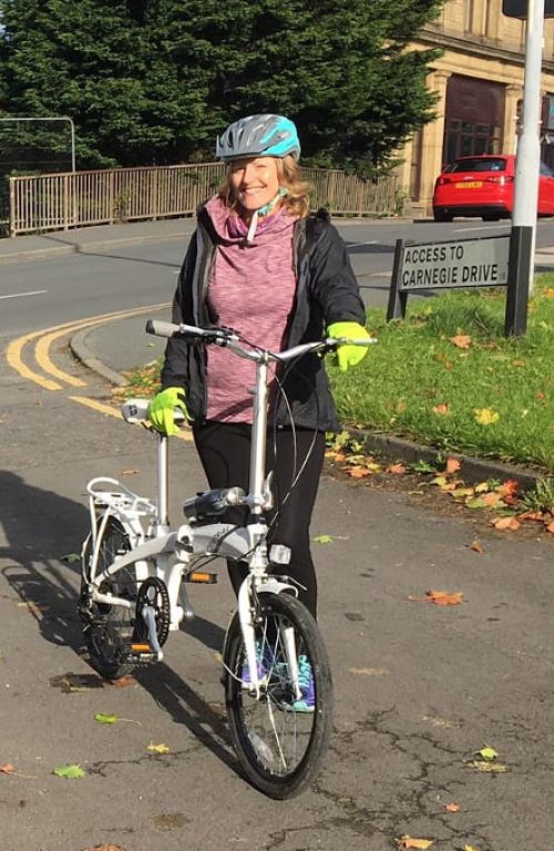 Woman standing next to folding bike.
