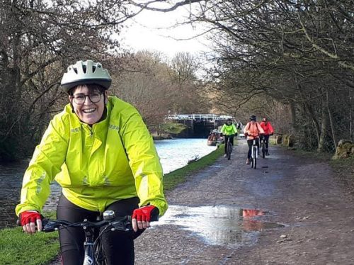 Woman on bike in yellow jacket and white helmet.