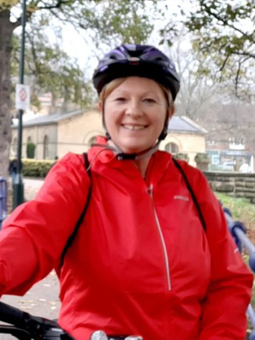 Woman in red jacket and cycle helmet.