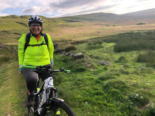 Smiling woman on bike in the hills.