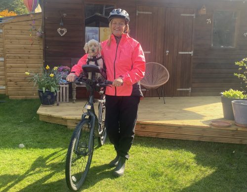 Lady cyclist standing by bike with dog