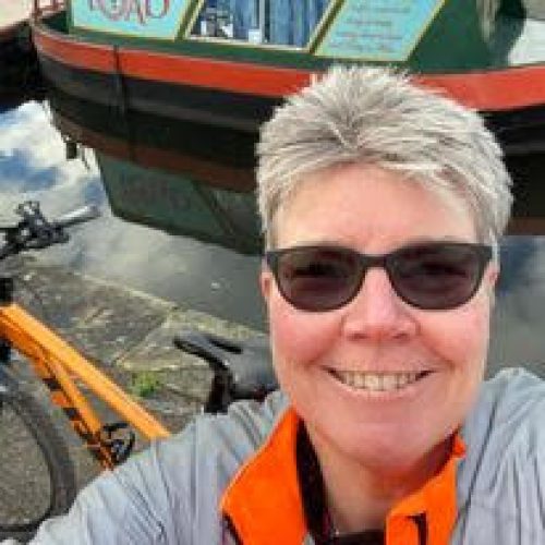 Smiling woman in sunglasses next to narrowboat.
